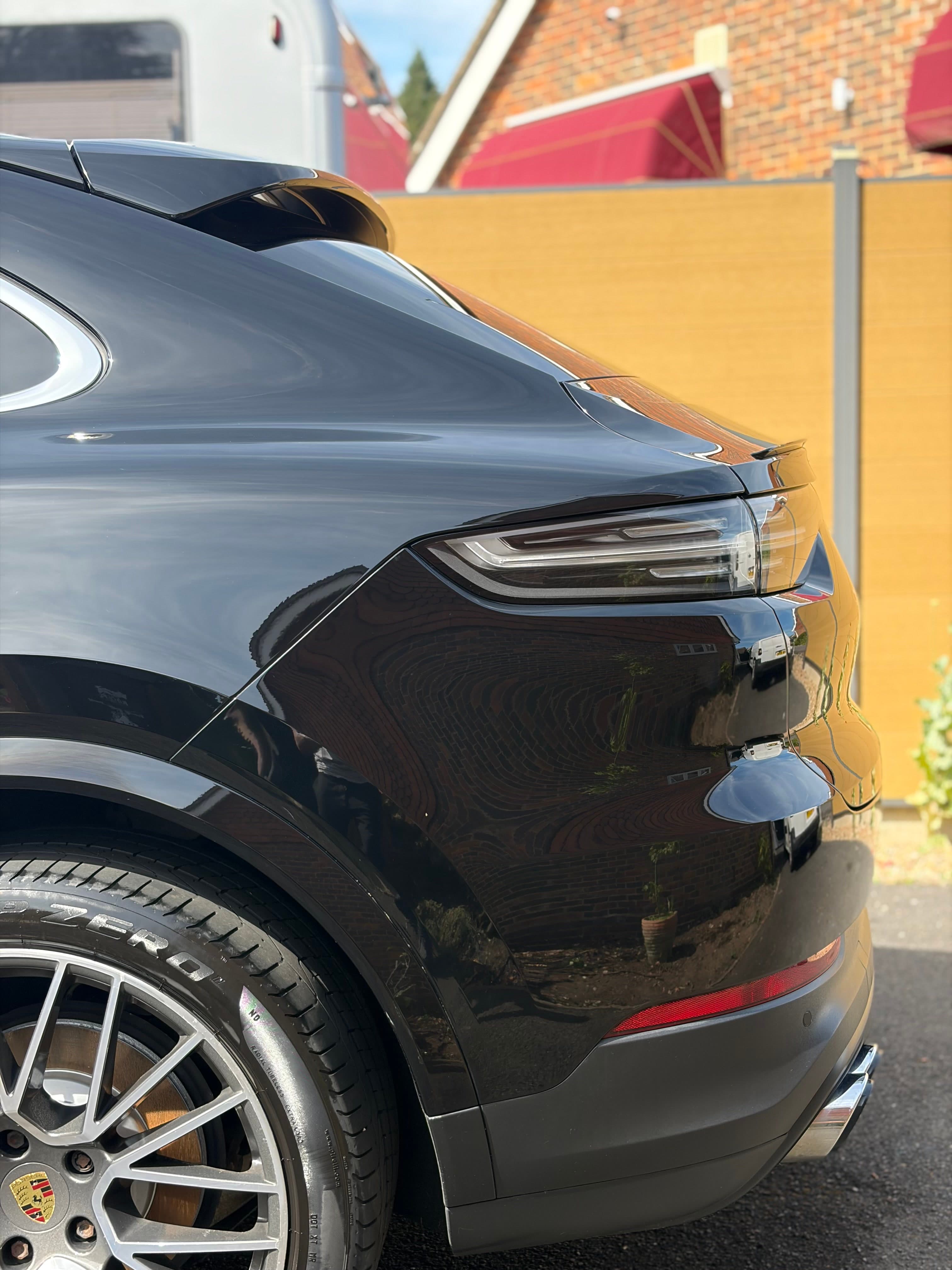 Deep gloss reflection across the rear quarter of a freshly detailed black Porsche Cayenne